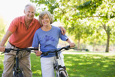 image of elderly couple riding bikes in park